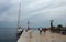 Sailboat, lookout and tourists on pier, cloudy sky and lightho