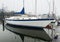 Sailboat moored in boat slip with reflection in still water on a foggy winter morning