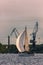 Sailboat moving past the cargo cranes