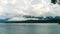 Sailboat navigating a calm lake with low clouds and mountains in the background. Villa La Angostura, Argentina