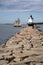 Sailboat Passes by Lighthouse on Edge of Breakwater in Maine