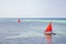 Sailboat with red sail on the sea. Reggata concept. Marine race. Yacht with red sail on tropical seascape. Summer recreation.