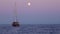 Sailboat and runabout anchored in Mediterranean sea against colorful sky and moon. White waving sail of yacht. Lipari