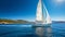 Sailboat sailing through the sea with an island and a clear blue sky on the background. Large sailing yacht cruising on a bright