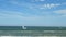 Sailboat in the sea in the clear weather, on sky with a few white clouds background. Sailing yacht in the blue sea near the coast.