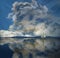 A sailboat is seen as a huge storm cloud is seen in the sky behind the boat