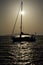 Sailboat with windmill crossing the sun