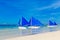 Sailboats with blue sails on a tropical beach. Journey and summer