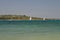 Sailboats on blue sea with seashore behind them