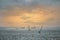 Sailboats in competition at dusk, passing by a lighthouse in Roscoff, France