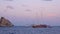 Sailboats floating near rocks in Mediterranean sea. Summer evening, sunset. Lipari Islands, Sicily, Italy