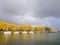 Sailboats at jetty in marina, trees in autumn colours and storm
