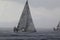 Sailboats navigating the sea in heavy rain.