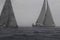 Sailboats navigating the sea in heavy rain.