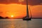 Sailboats silhouette against a fiery sunset over a serene waterway