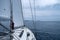 Sailing in Aegean sea, Greece. Sailboat with open white sail, cloudy sky and rippled sea