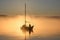 sailing boat with crew of two in misty morning sunrise