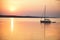 Sailing boat floats in the calm sea at sunrise