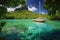 sailing boat moored in tranquil lagoon against tropical backdrop