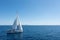 Sailing boat with open white sails, blue sky and rippled sea background