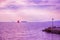 Sailing boat with a red sail on the sea. Purple toned photo