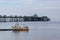 A sailing boat sits by the pier on Llandudno promenade