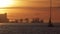 Sailing boats during orange sunset - industrial cranes on the background