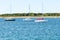 Sailing boats tied up to mooring buoys in a bay with a sandy beach in background