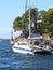 Sailing catamaran sails along the rocky green coast past the red literary sign - the fairway lighthouse. City of Sibenik in the Da