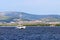 Sailing catamaran sails along the rocky green coast past the red literary sign - the fairway lighthouse. City of Sibenik in the Da