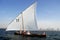 Sailing Dhow Against The Distant Cityscape Of Duba