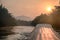 Sailing long-tail boat with sunrise on bridge in river kwai