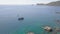 Sailing ship in blue sea water and rocky cliff aerial view. Drone shot boat sailing in sea bay and mountain cliff on
