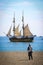 Sailing ship next to the coast. Napoleonic soldier on a beach. Historical reenactment