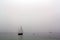 Sailing ship and paddle surfer in a misty day