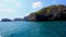 Sailing of speed boat next to a rock islands