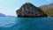 Sailing of speed boat next to a rock islands