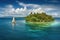 sailing yacht cruising past idyllic tropical island