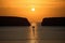 sailing yacht rounding headland, with the sun setting in the background