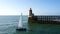 Sailing yacht at sea against the backdrop of a lighthouse.