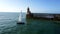 Sailing yacht at sea against the backdrop of a lighthouse.