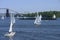 Sailing yachts and large bargefloating on the Dnieper river, bridge and island on a background