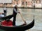 Sailor driving tourists in a gondola in Venice