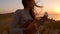 Sailor hippie caucasian girl playing ukulele guitar at beautiful sunset near sea. HD slowmotion.