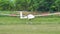 Sailplane landing with the spoilers open in a green grass airfield