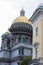 Saint Isaac`s Cathedral golden cupola dome, statues, granite columns close up on grey cloudy sky background