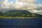 Saint Kitts Island landscape - distant view from water of a hill slope with sun and shade patches