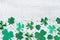 Saint Patricks Day background with green shamrock on white rustic board top view.