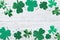 Saint Patricks Day border with green shamrock on white rustic board top view.