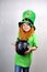 Saint Patricks Day. Funny smiling small girl with decorative red beard, green clover leaf on her cheek and leprechaun hat, dressed